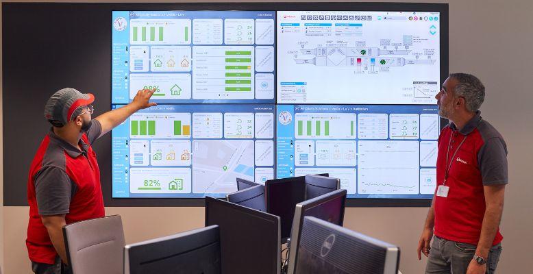 Two Veolia employees look over a data dashboard of multiple screens
